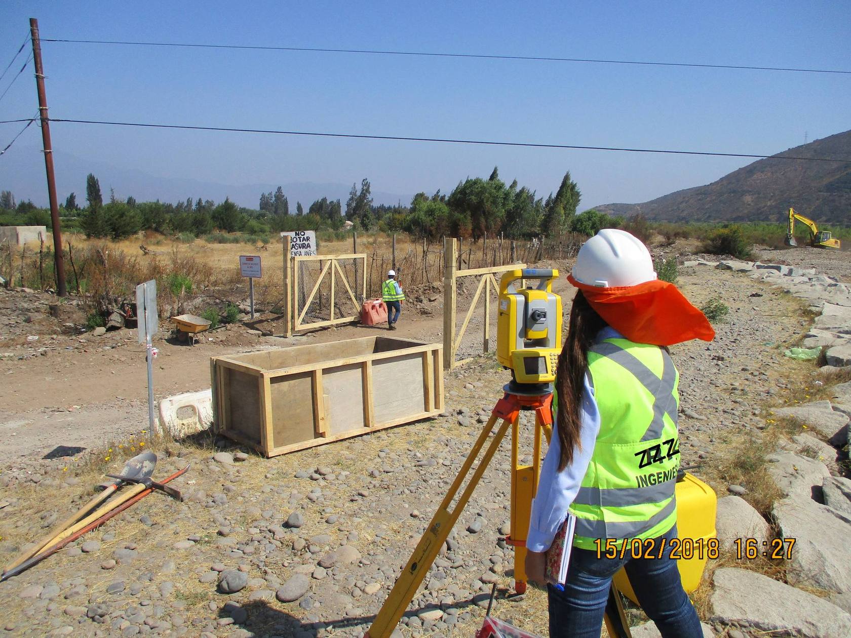 Ingeniera topógrafa realizando levantamiento con estación total en faena de terreno